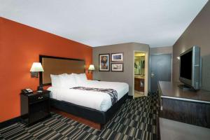 a hotel room with a bed and a flat screen tv at La Quinta by Wyndham Memphis Airport Graceland in Memphis +19 photos