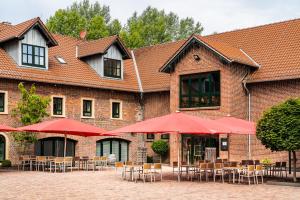 un edificio con mesas, sillas y sombrillas rojas en ClassicX Landhaus & Hotel - Bed & Breakfast, en Gensingen