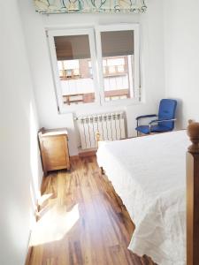 1 dormitorio con 1 cama blanca y 2 sillas azules en Homelunead Apartamento en Gijon Centro al lado de la Playa, en Gijón