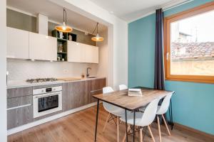 - une cuisine avec une table en bois et des chaises blanches dans l'établissement Santa Croce Flat - Modern Apartment, à Florence