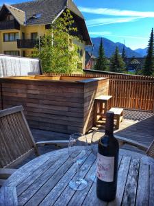 a bottle of wine sitting on a wooden table with a glass at House Neza in Kranjska Gora