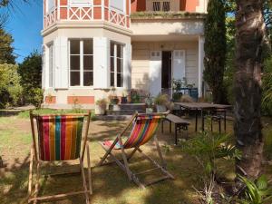 two chairs and a table in front of a house at Le Quatre Allée Stella Arcachon in Arcachon