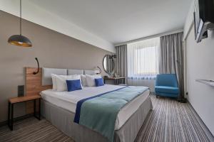 una habitación de hotel con una cama grande y una silla azul en Aerostar Hotel, en Moscú