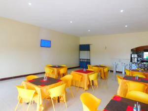 a dining room with tables and yellow chairs at Range Lands Hotel in Moroto