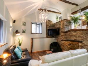 a living room with a couch and a brick wall at Elvan Cottage in Liskeard