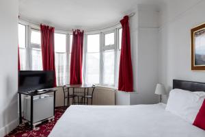 a bedroom with a bed with red curtains and a desk at Euro Hotel Harrow in Harrow