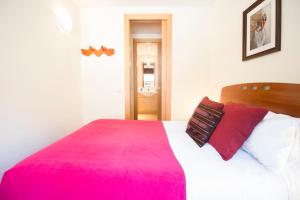 - une chambre avec un grand lit et une couverture rose dans l'établissement Apartaments Les Terrasses del Tarter, au Tarter