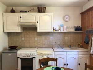 a kitchen with white cabinets and a stove and a sink at appartement Saint-Antoine in Toulon-sur-Arroux