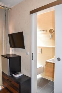 a bathroom with a toilet and a tv on the wall at Boutique Hotel Sena in Berlin