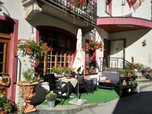 um pátio exterior com uma mesa, cadeiras e flores em Hotel Escher em Leukerbad