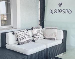 - un canapé blanc avec des oreillers sur une terrasse couverte dans l'établissement AjoieSpa, à Porrentruy