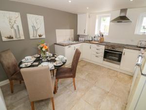a kitchen with a table and chairs and a kitchen with white cabinets at Rhiw Afallen in Caernarfon