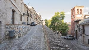 una calle vacía en un pueblo con un muro de piedra en Apartamento San Cipriano con parking incluido, en Toledo