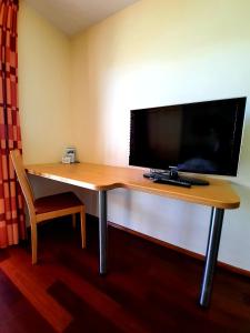 a desk in a hotel room with a tv and a laptop at Das smarte Hotel garni in Höchst