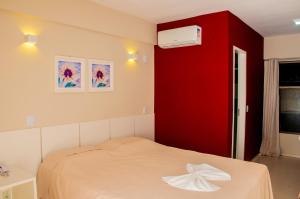 een slaapkamer met een bed met een rode muur bij Murano Center Hotel in Limoeiro do Norte