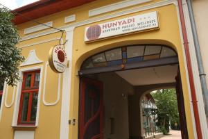 un edificio amarillo con una señal sobre una puerta en Hunyadi Panzió-Apartman en Makó