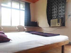 a bed in a room with a window and a window at MTDC Meghdhanush park in Igatpuri