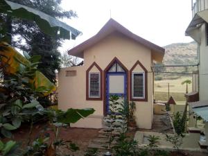 a small small house with a blue door at MTDC Meghdhanush park in Igatpuri