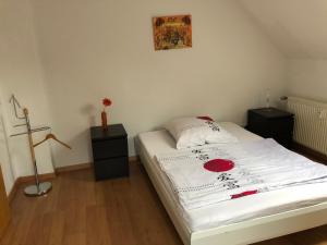 a bedroom with a bed with white sheets and red flowers at FeWo Kerstin Rossbacher in Solingen