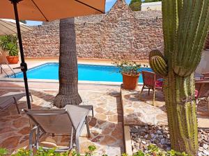 a patio with chairs and an umbrella and a pool at Palacio Sant Salvador in Artá