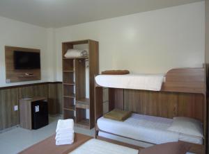 a room with two bunk beds and a flat screen tv at Pousada Vô Quintino in Penha