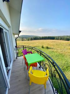d'un balcon avec une table verte et des chaises colorées. dans l'établissement Apartman Narcis 2 Divcibare, à Divčibare