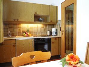 eine Küche mit Holzschränken und einem Tisch mit Blumen in der Unterkunft Haus Kurz Matthäus in Walchsee