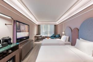 a hotel room with two beds and a flat screen tv at Mercure Nanjing Downtown in Nanjing