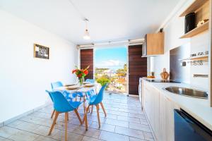 a kitchen with a table and blue chairs in a kitchen at Studio du Lagon vue mer St Gilles les Bains Centre 500m de la plage in Grand Fond