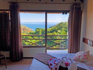 a bedroom with a large window with a view of the ocean at Pousada Amancay in Búzios