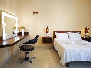 a bedroom with a bed and a chair and a mirror at Arraial da Lage Hospedaria in Resende Costa