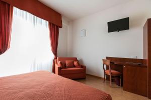 1 dormitorio con cama, escritorio y silla en Hotel Conradi, en Chiavenna