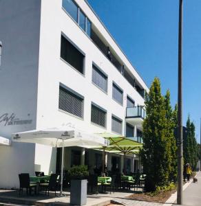 um edifício branco com mesas e guarda-sóis em frente em Zimmer - Modernes Apartment mit 45 qm. em Straubing