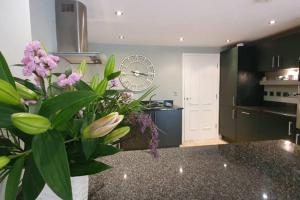 a kitchen with a counter with purple flowers and a clock at Stylish Stamford Central, Free Parking in Stamford