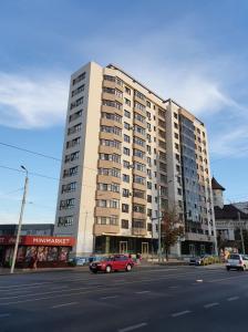 a large building with a red car in front of a street at Unique Hotel Apartments Rond Vechi in Iaşi