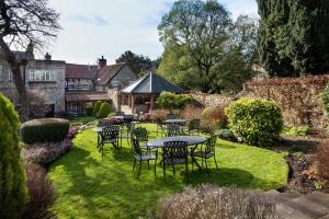 un patio con mesas y sillas en un jardín en The Black Swan - The Inn Collection Group en Helmsley