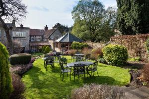 a patio with tables and chairs in a garden at The Black Swan - The Inn Collection Group in Helmsley