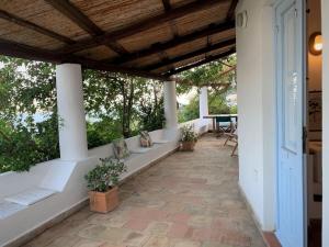 eine Außenterrasse mit weißen Säulen und einem Tisch in der Unterkunft La Casa di Tommy - Santa Marina Salina in Santa Marina Salina