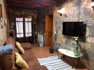 een woonkamer met een bank en een tv aan een stenen muur bij Casa rural Pérez Martín in Sancti Spíritus