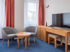 a hotel room with a television and two chairs and a table at Wellness & Spa Relax Frymburk in Frymburk