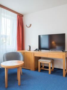 a room with a tv and a desk with a chair at Wellness & Spa Relax Frymburk in Frymburk