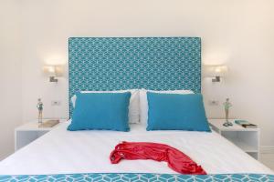 a bed with two blue pillows and a red robe on it at Gala Residence Villa Giovanna in Ravello