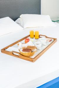 a tray of food on a bed with two glasses of orange juice at Drops Motel São José do Rio Preto in Sao Jose do Rio Preto