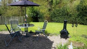 a table and chairs with an umbrella and a grill at Hazler Lodge in Church Stretton