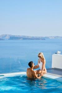 un hombre y una mujer sentados en una piscina en Filotera Suites en Oia