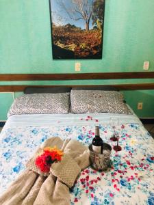 Una cama con flores y copas de vino. en Pousada Recanto da Chapada, en Mucugê