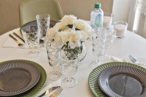 une table avec des assiettes, des verres et un vase de fleurs blanches dans l'établissement Via Roma Luxury Apartment by Wonderful Italy, à Gênes