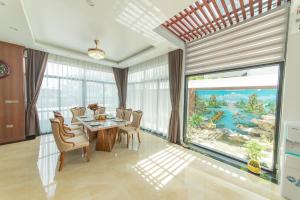jadalnia ze stołem i krzesłami oraz dużym oknem w obiekcie Villa FLC BT 10 -04 w Ha Long