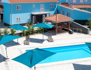 a pool with umbrellas and chairs and a blue building at Villa Montês Guesthouse in Coja