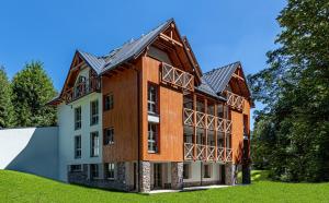 a large wooden building on top of a green field at Apartmán B Harrachov in Harrachov